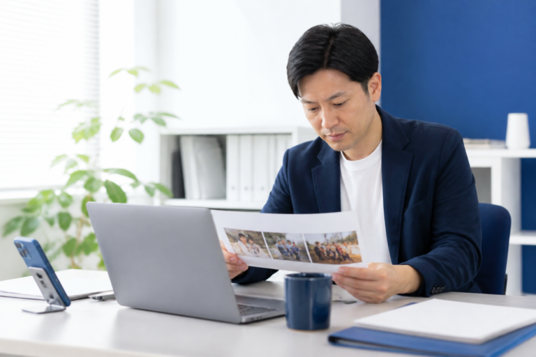 地方議員事務所で地域活動の写真を確認しながらSNS投稿を準備する様子