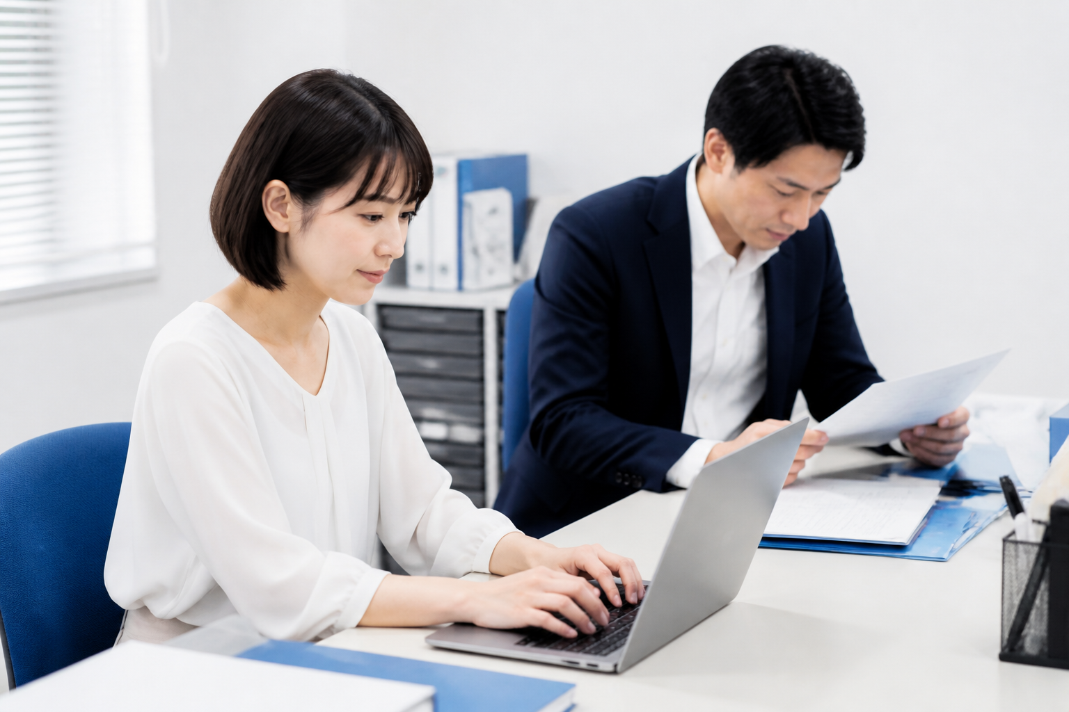 SNS投稿の下書きを準備する事務所スタッフと資料を確認する議員