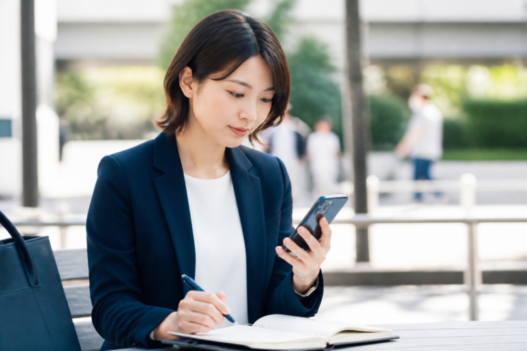 街頭活動後にスマートフォンの写真と活動メモを確認してSNS投稿文を準備する担当者